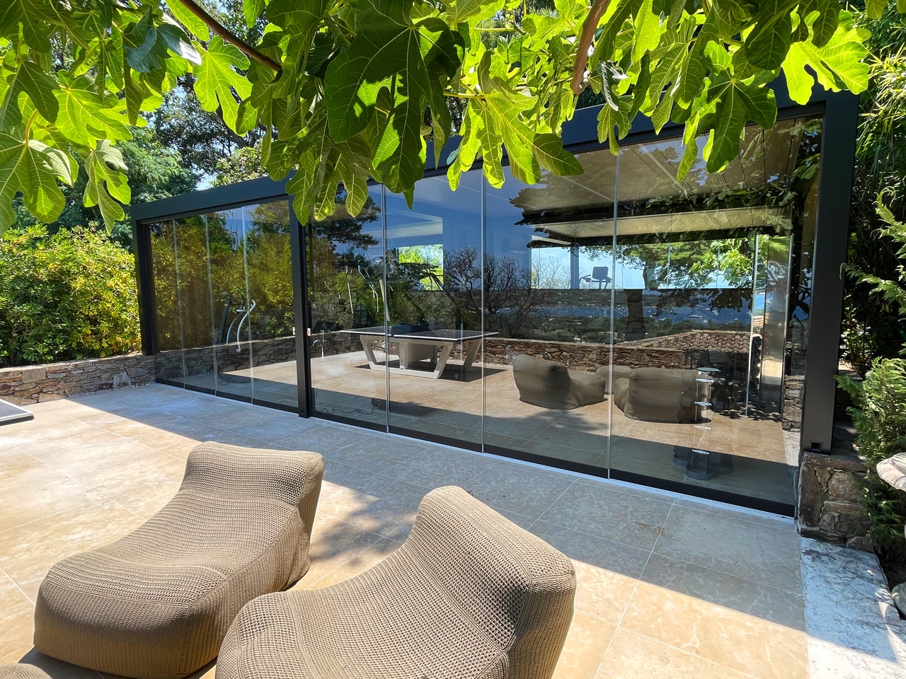 Pergola bioclimatique IMAGO Corradi avec fond miroir et côtes en lambris d’ipé, fermeture de la façade avec baies coulissantes sans châssis à Saint Tropez, Var, 83