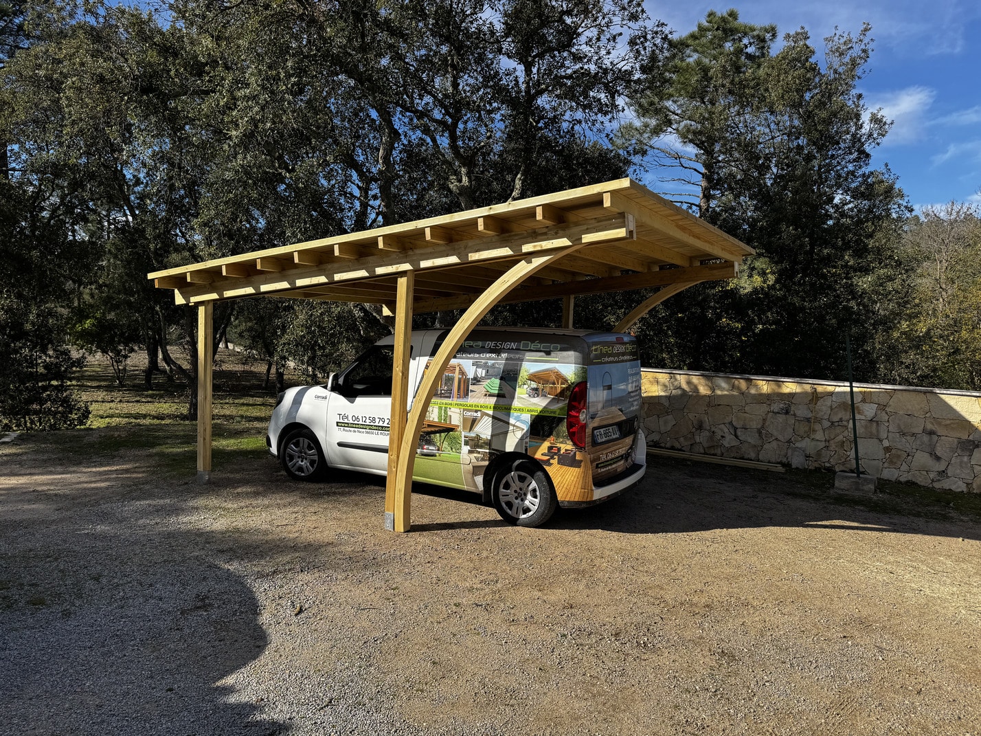 Réalisation d'un abris voiture / Carport simple autoportante avec couverture en lambris bois + shingles vert. La structure est entièrement réalisée en pin autoclavé lamellé-collé. Piliers décentrés vers l'arrière avec arches de soutien pour pouvoir manoeuvrer facilement avec un véhicule.